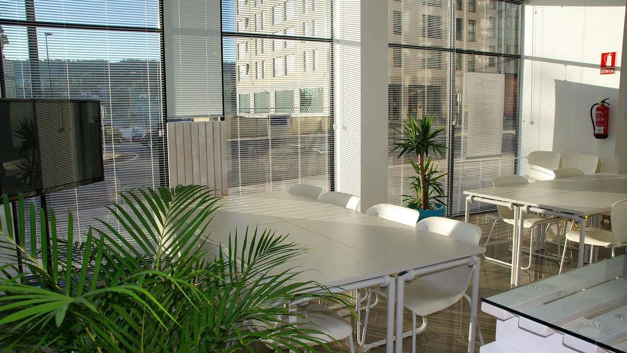 Espace de coworking lumineux avec de longues tables et des plantes