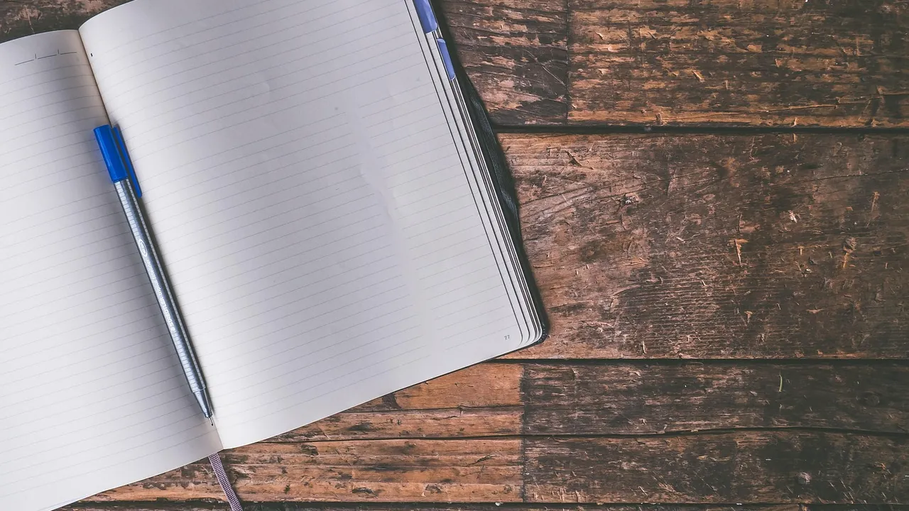 Carnet ouvert et stylo bleu posés sur une table en bois