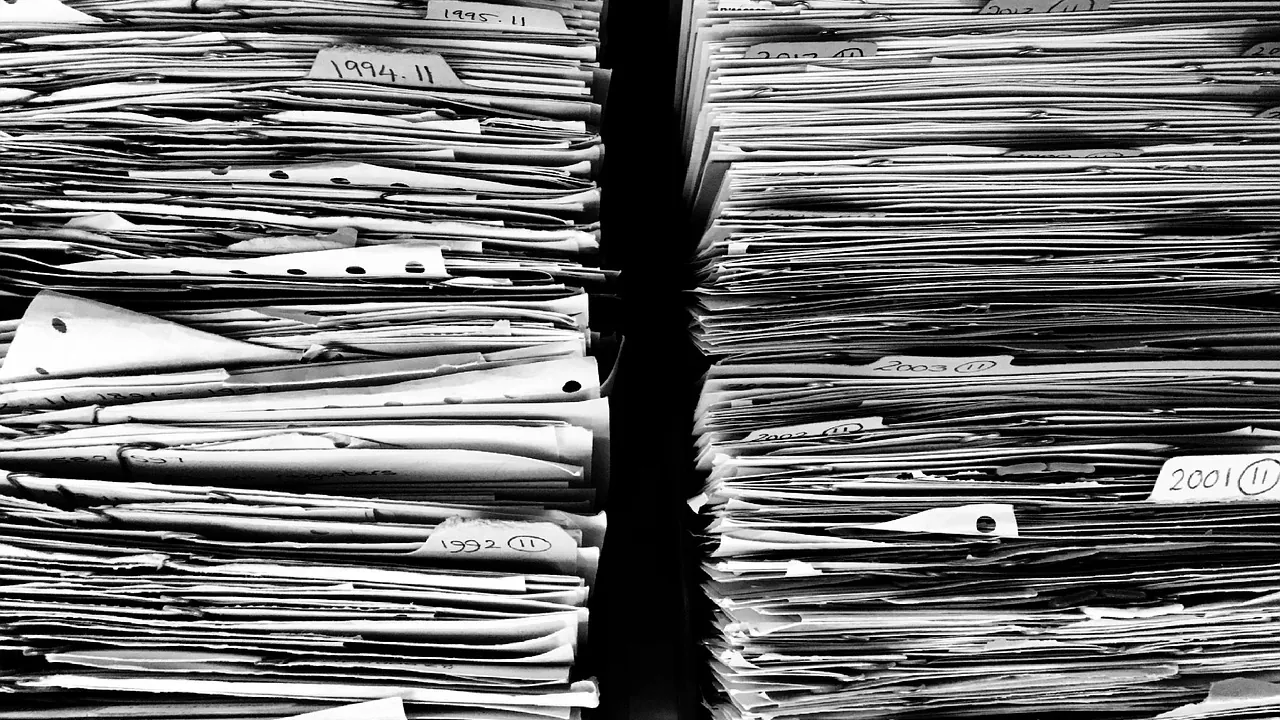Piles de dossiers papier accumulés dans des archives