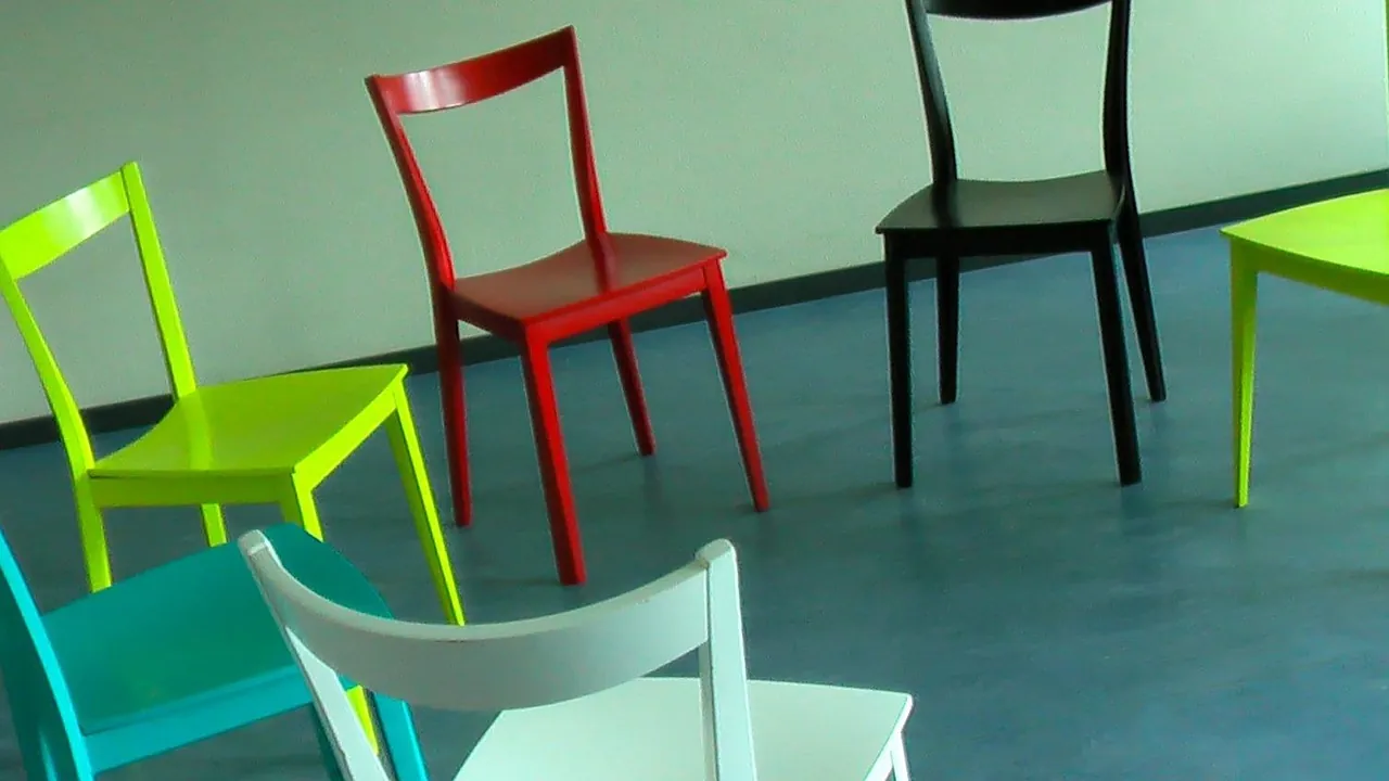 Chaises de couleurs différentes disposées librement dans une salle